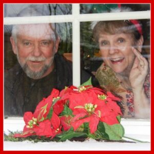 Picture of Patricia and her husband Les looking out a window decorated for Christmas