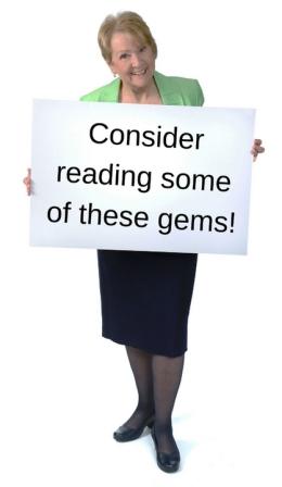 Picture of Patricia Morgan holding a sign that says "Consider reading some of these gems!"